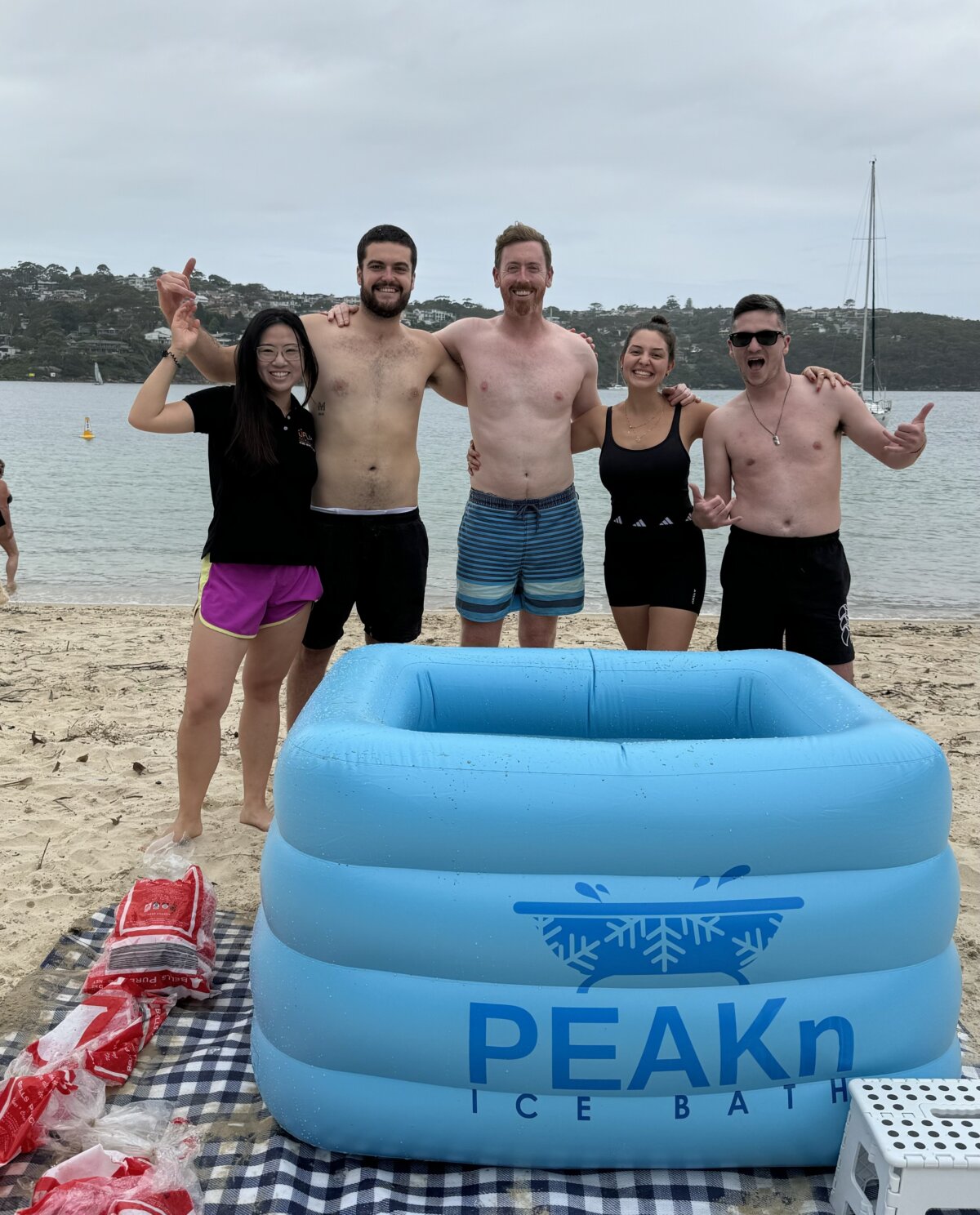 Group of happy people standing in front of ice bath.