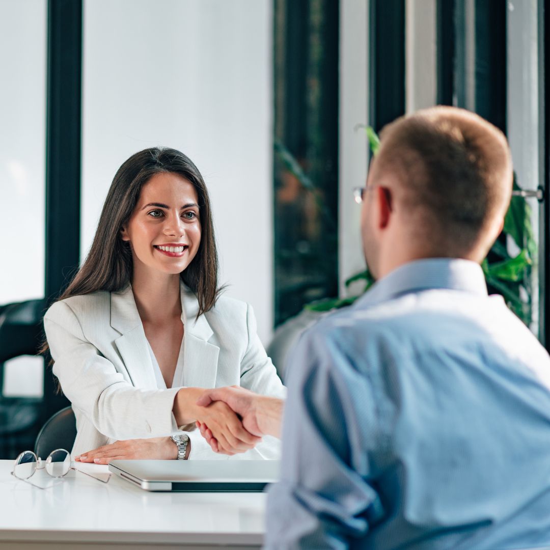 A woman shaking a man's hand agreeing to hire him.